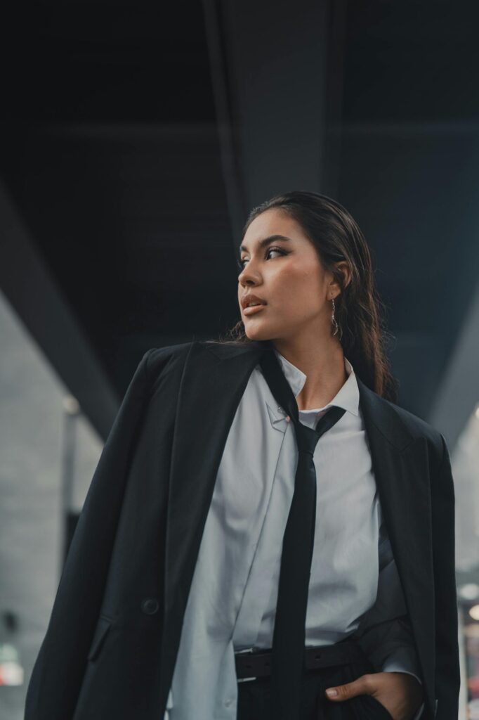 pexels-photo-27874690-27874690 Confident young woman in elegant black suit under a city bridge, exuding leadership and style.