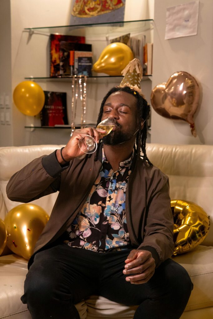 pexels-photo-30871232-30871232 Man enjoying a birthday celebration with champagne and golden balloons indoors.